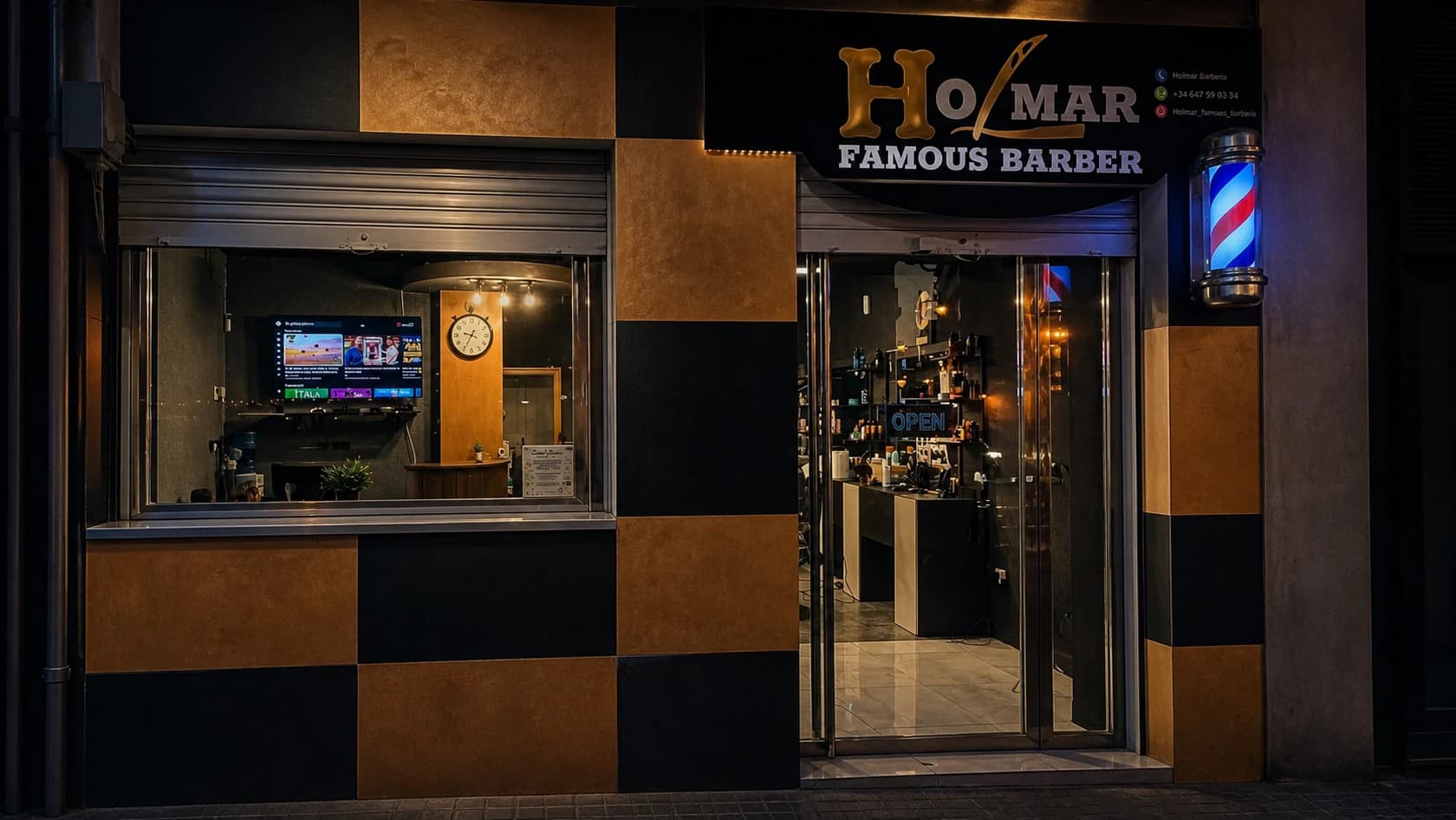 Fachada nocturna de Holmar Famous Barber con el rótulo iluminado y el interior visible